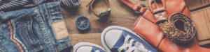 An array of clothing: blue jeans, shirt, compass, watch, handbag, belt, wallet, sneakers